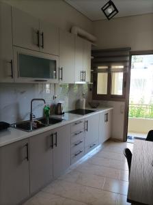 a kitchen with white cabinets and a sink at Zeta ' s house in Nafpaktos