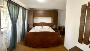 1 dormitorio con cama de madera y ventana en Casa de sub Salcie, en Curtea de Argeş