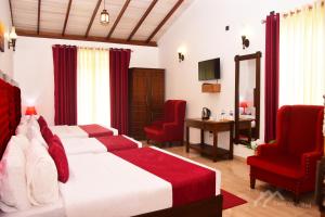 a bedroom with a bed and two red chairs at Twin Villa Red in Nuwara Eliya