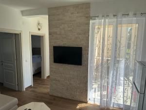 een woonkamer met een televisie aan een bakstenen muur bij Niki Apartments in Ulcinj