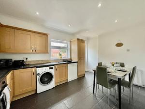 a kitchen with a table and a washing machine at Modern 3 Bed Romford Home (Free Parking) in Havering atte Bower