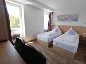 una habitación de hotel con 2 camas y una silla en Meerbuscher Hof, en Meerbusch