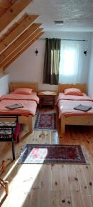 a bedroom with two beds and a window and wooden floors at Top Hill Lodge in Kolašin