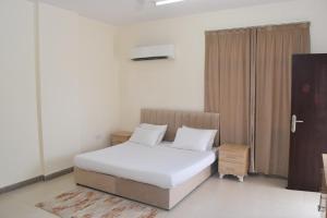 sypialnia z łóżkiem z białą pościelą i białymi poduszkami w obiekcie Aknan 01 - Center Market w mieście Salala
