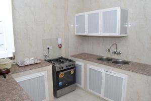 uma pequena cozinha com um fogão e um lavatório em Aknan 01 - Center Market em Salalah