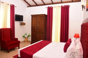 a bedroom with a bed and a chair and red curtains at Twin Villa Red in Nuwara Eliya