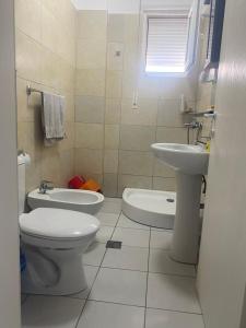 a white bathroom with a toilet and a sink at Sea retreat apartment in Himare