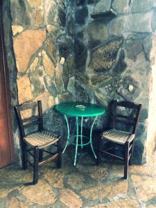 a green table and two chairs next to a stone wall at Yard in Astirákion