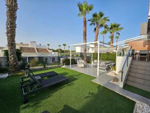 a backyard with a lawn with a gym and palm trees at Casa Veran at La Finca Golf in Algorfa