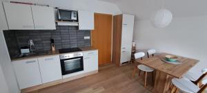 a kitchen with white cabinets and a table with chairs at Apartma Bine in Bled
