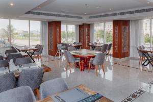 Salalah International Hotel في صلالة: غرفة طعام مع طاولات وكراسي ونوافذ