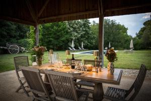 a wooden table in a pavilion with chairs around it at Les Cieux de Saint-Félix, Maison d'Hôtes & SPA in Saint-Félix-de-Villadeix