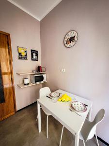 a white dining room table with chairs and a clock on the wall at Alloggio Rumore di Onde in Rapallo