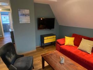a living room with a red couch and a chair at Dat Smucke Reethus Dachgeschoss in Born