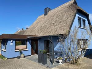 a blue house with a thatched roof at Dat Smucke Reethus Dachgeschoss in Born