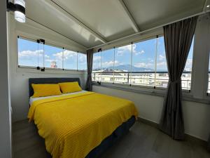 a bedroom with a yellow bed and large windows at Stan na dan V&L-Lukavica in Sarajevo