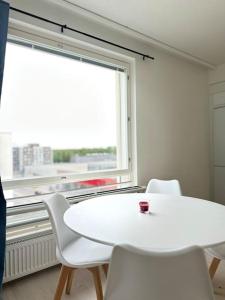 una mesa y sillas blancas en una habitación con ventana en Huoneisto juna aseman vieressä en Vantaa