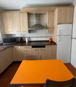 uma cozinha com uma mesa laranja e um frigorífico branco em Casa Nostra Matarranya em Calaceite