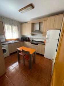 a kitchen with a table and a white refrigerator at Casa Nostra Matarranya in Calaceite