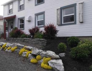 uma casa com uma parede de pedra em frente a um quintal em Le vieux poulailler édifice patrimonial New-Richmond Gaspesie em New Richmond