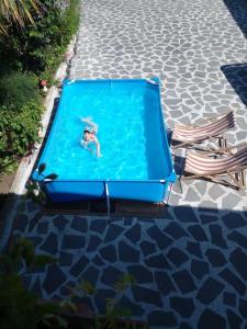 Una mujer está nadando en una piscina azul en una piscina. en Guesthouse Giorgi, en Telavi