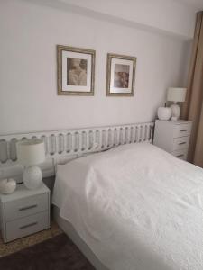 - une chambre avec un lit blanc et deux photos sur le mur dans l'établissement Cerca del Mar, à Dénia