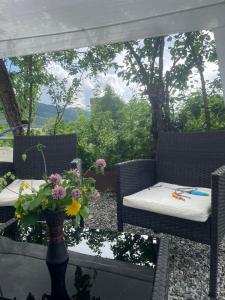 a patio with two chairs and a table with a vase with flowers at Cottage - Location Lanchvali in Mestia