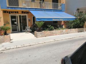 una tienda al lado de una calle con un toldo azul en Megaron Hotel, en Pozzallo