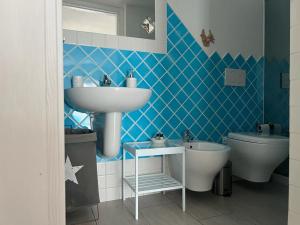 baño de azulejos azules con lavabo y aseo en Da Fede, en Capo Testa