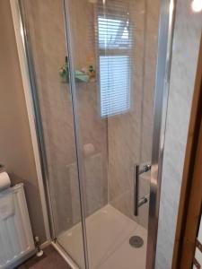 a shower with a glass door in a bathroom at Millfields 4 berth caravan DG & CH family's only and lead person must be over 30 in Ingoldmells
