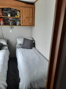 um pequeno quarto com 2 camas e um armário em Millfields 4 berth caravan DG & CH family's only and lead person must be over 30 em Ingoldmells