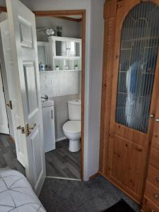 a bathroom with a toilet and a sink and a door at Millfields 4 berth caravan DG & CH family's only and lead person must be over 30 in Ingoldmells