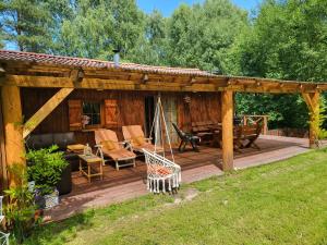 una terraza de madera con hamaca y una casa en Borowe Chatki nad Lubiszewem en Lipusz