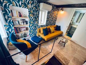 a living room with a yellow couch and two blue chairs at Triplex de Saint-Paul Free public parking in Saint Paul de Vence