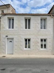 een wit bakstenen huis met een witte deur bij Agréable maison de ville in Saujon