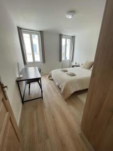een slaapkamer met een bed, een tafel en 2 ramen bij Agréable maison de ville in Saujon
