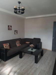 een woonkamer met een zwarte bank en een tafel bij Lovely_apartment in Tbilisi City