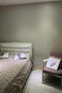 een slaapkamer met een bed en een stoel met een foto bij Lovely_apartment in Tbilisi City