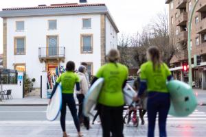 grupa ludzi chodzących po ulicy z deskami surfingowymi w obiekcie Zarautz Surf House w mieście Zarautz