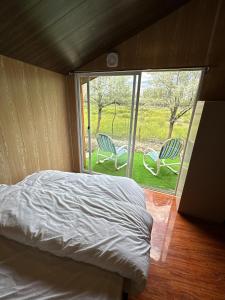 a bed and two chairs in a room with a window at MONTAGNA PODS in Skardu