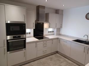 a kitchen with white cabinets and black appliances at Admiral's View - Apartment 1 in Scarborough