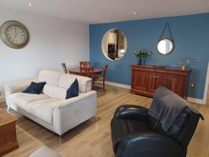 a living room with a couch and a chair and a clock at Admiral's View - Apartment 1 in Scarborough