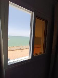 een raam met uitzicht op het strand bij PLAYA HOTEL in Dakhla