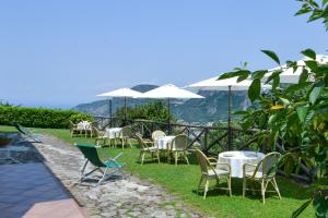 een groep stoelen en tafels met witte parasols bij Villevieille in Piano di Sorrento