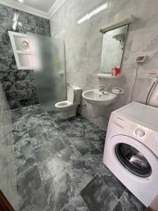 a bathroom with a toilet sink and a washing machine at Fully Furnished 2bedroom apartment, Salalah, Oman in Salalah