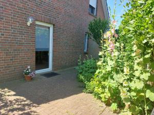 a brick building with a door and a bush with flowers at Ferienwohnung Huber,Mönchgut in Middelhagen