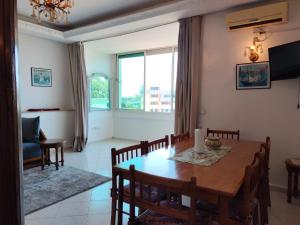 una sala da pranzo con tavolo, sedie e finestra di Élégant appartement 3 chambres a Rabat