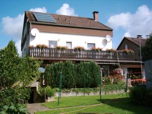 a white house with a balcony with a solarium at Pension Familie Schwarz GbR in Alhausen