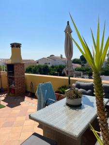 a patio with a table and a palm tree and an umbrella at SANT MORI GRAN TERRASSA in Empuriabrava
