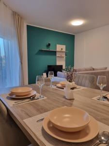 una mesa de comedor con platos y copas de vino en Apartmani Toni, en Drniš